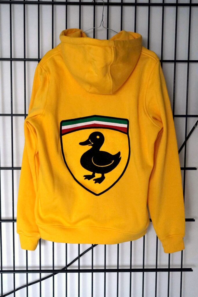 Gelber Hoodie, Rückenansicht: gesticktes Wappen mit schwarzer Ente und grün-weiss-roten Streifen