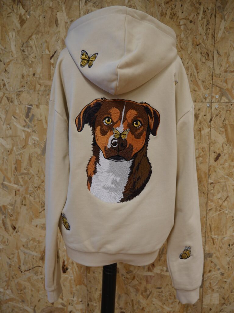 Cremefarbener Oversize Hoodie von hinten: gesticktes Hundeporträt und goldene Schmetterlinge