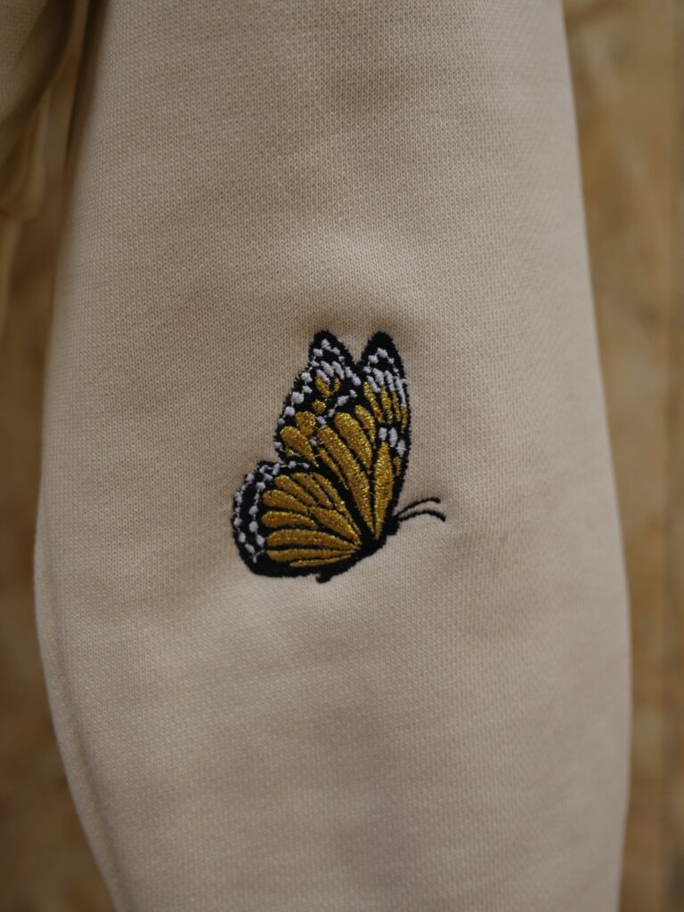 Gestickter Schmetterling aus goldenen Metallfäden am Ärmel